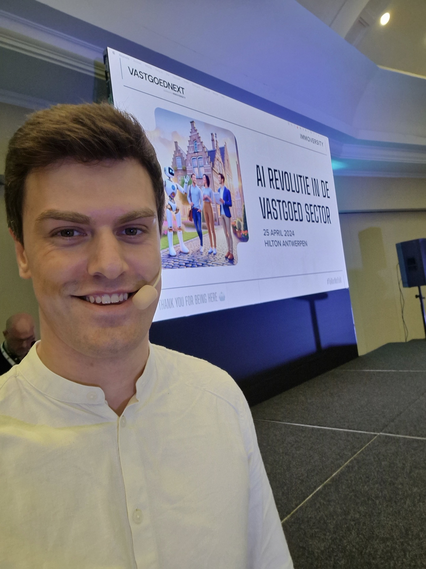 Spreker met headset voor het podiumscherm van VastgoedNXT.