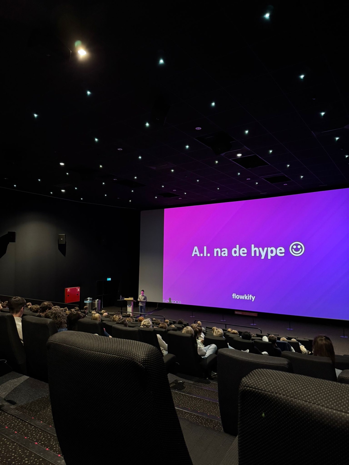 Auditorium met publiek en een scherm met de titel A.I. na de hype.