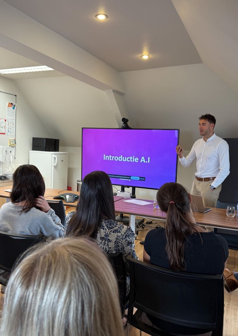 Medewerkers volgen een sessie, op het scherm de slide Introductie A.I.